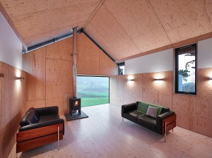 A crumbling old stone mill was transformed when architects inserted a modern prefabricated timber home into the structure. Spruce walls and a wood burning stove make the living room cozy while black leather couches and big windows create a modern look. 