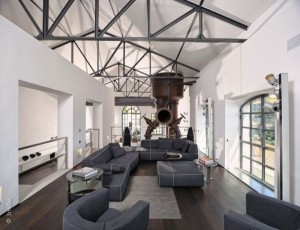 A water cleaning station in France was converted into a modern home. The living room has grey couches, dark wood floors and houses the original three-storey tall water tank. 