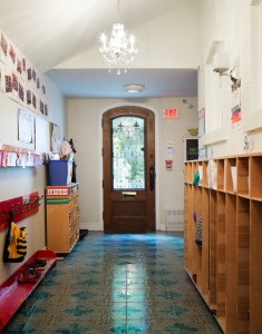 White heritage home with wood door, vintage chandelier and tile. Was once a stable.